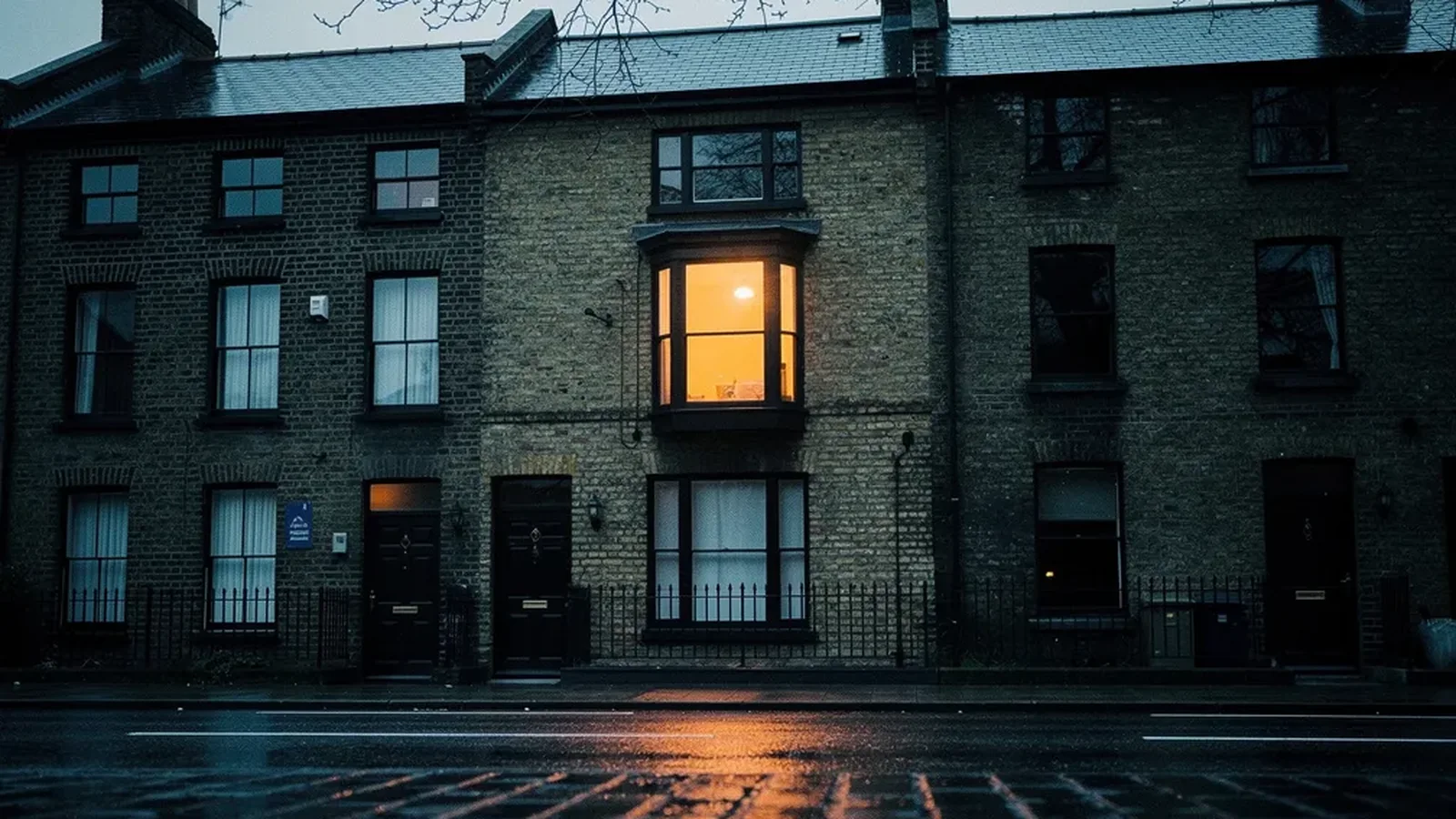 A terraced street at dusk with one window lit